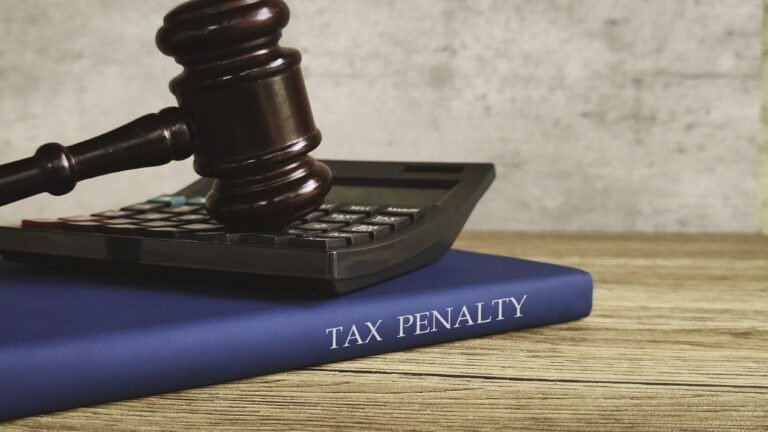 A gavel and calculator on a book titled "TAX PENALTY" representing financial and legal consequences.